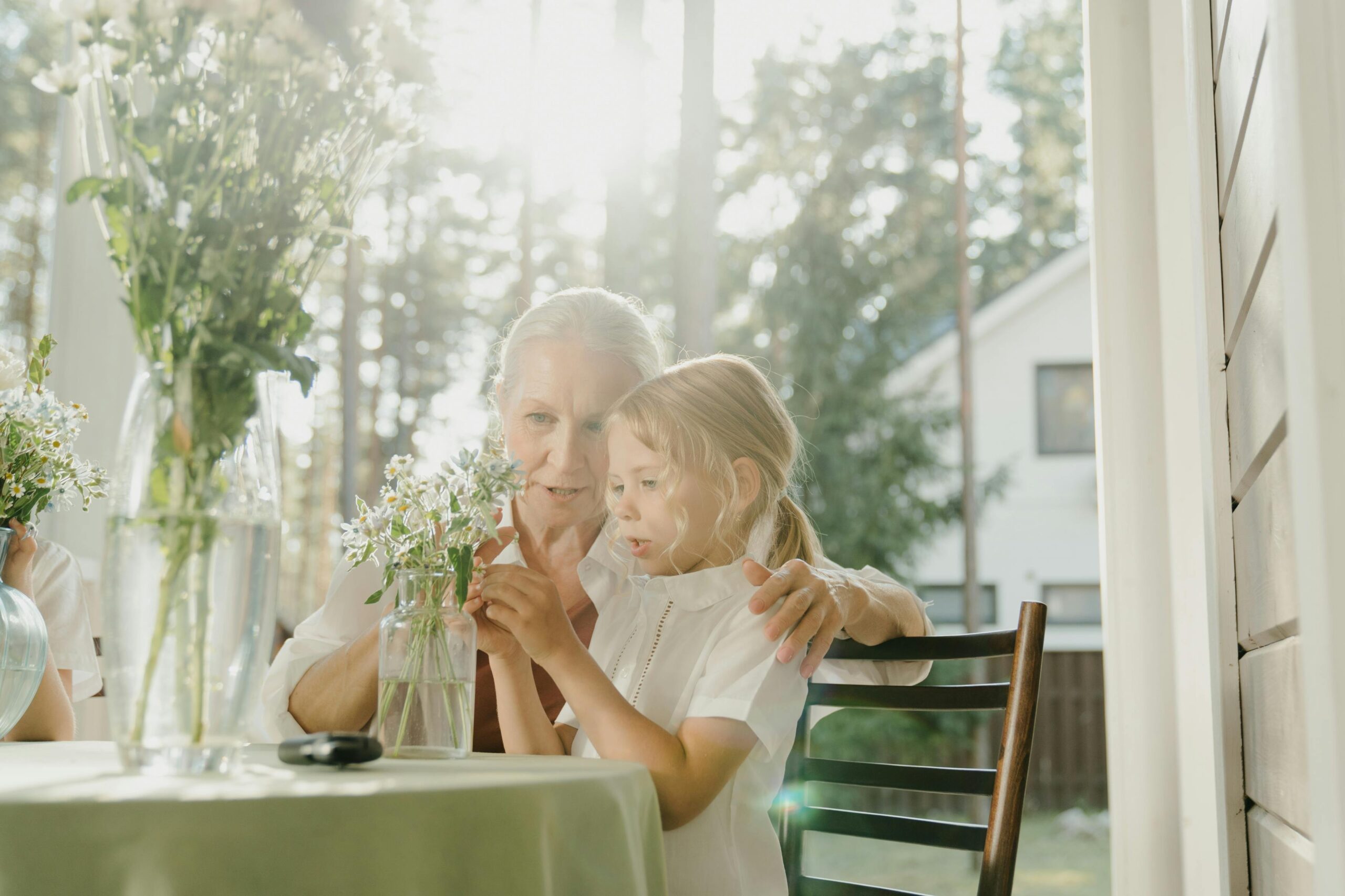 A grandmother and grandchild arranging flowers on a sunny porch, sharing a tender bond.